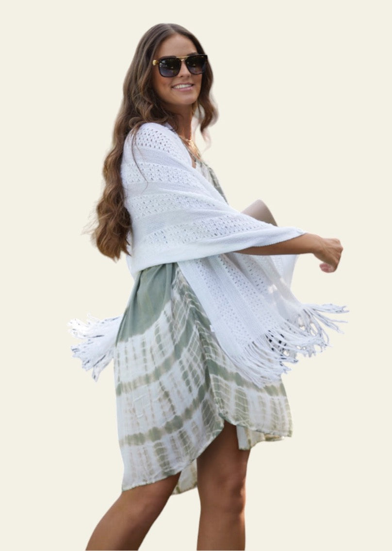 White Knitted Cardishawl. The soft, textured knit creates a cozy and breathable feel, while the loose, open design adds effortless charm and movement. The piece falls gracefully, offering a stylish, laid-back look that remains both comfortable and chic.